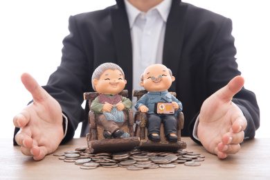 穿着正装的男性双手呵护着放在美元硬币上的老两口模型