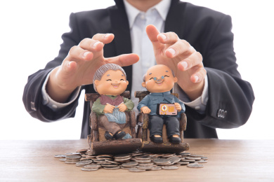 穿着正装的男性双手呵护着放在美元硬币上的老两口模型