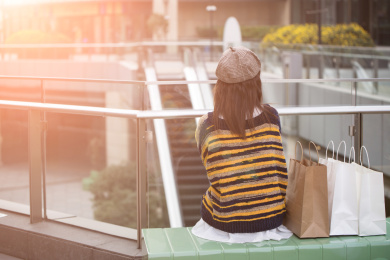 逛街购物后坐在商场椅子上休息的年轻女性背影