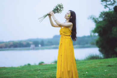 湖边穿黄裙子手拿鲜花的女孩