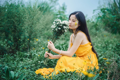 草坪上穿黄裙子手拿鲜花的女孩