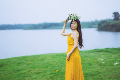穿黄裙子手捧鲜花站在草地的美丽女孩
