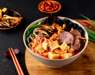 黑色背景上餐具里盛放的牛肉泡馍
