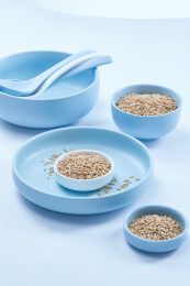 白色背景上的青釉瓷餐具装的燕麦米（莜麦）
