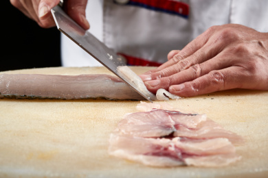 白色砧板上厨师用精湛的刀工展示鱼脍(生鱼片)的切片过程