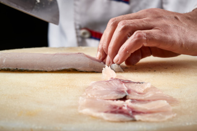 白色砧板上厨师用精湛的刀工展示鱼脍