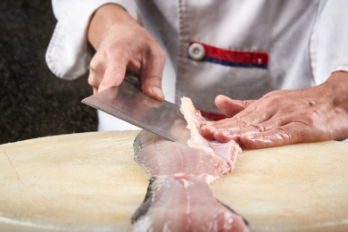 白色砧板上厨师用精湛的刀工展示鱼脍