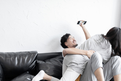 一对年轻情侣在客厅的沙发上争抢手机