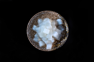 摆放在黑色桌面上陶瓷碗中的白色椰子肉，