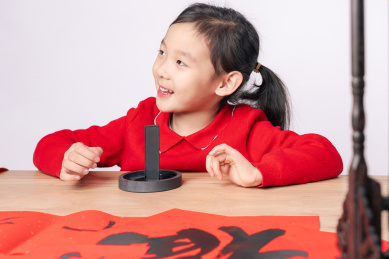 在木质书案上研墨的中国女孩