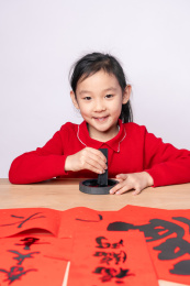 在木质书案上研墨的中国女孩