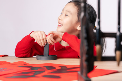 在木质书案上研墨的中国女孩