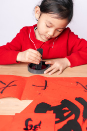 在木质书案上研墨的中国女孩