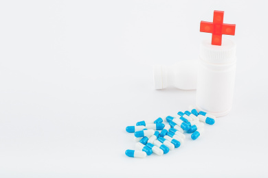 白色背景纸上放着蓝白色胶囊和白色药瓶。