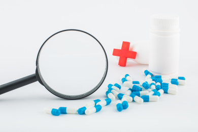 白色背景纸上放着蓝白色胶囊和白色药瓶。