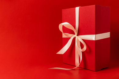 立起来放在红色背景的绑着香槟色带子的红色礼品盒