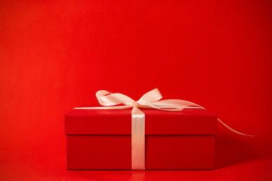 竖着放在红色背景的绑着香槟色带子的礼物盒包装