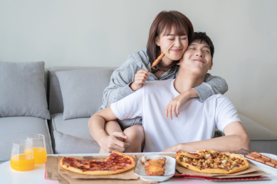 年轻情侣在客厅沙发前吃披萨
