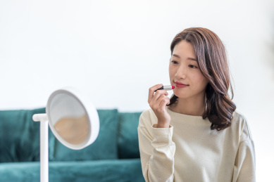 一名年轻漂亮女性在梳妆镜前涂口红