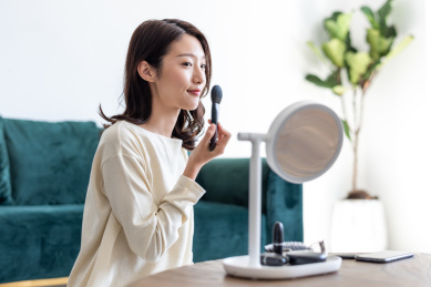 年轻漂亮女性在镜子前使用化妆刷