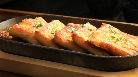 木板上椭圆形铁板里的小葱煎豆腐