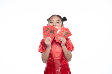 一位小女孩儿手拿着红包面向镜头微笑