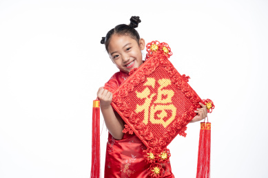 一位小女孩儿手拿着福字面向镜头微笑