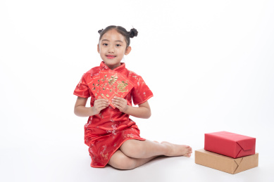 一位小女孩儿坐在地上拿着红包微笑