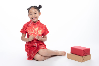 一位小女孩儿坐在地上拿着红包微笑