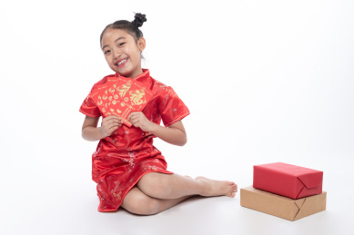 一位小女孩儿坐在地上拿着红包微笑