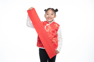 一位小女孩儿手拿着对联面向镜头微笑