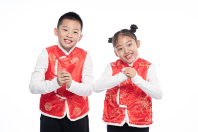 一男一女两个小孩儿面向镜头做出拜年的姿势