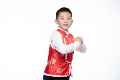 一位男孩儿对着镜头做出拜年的姿势