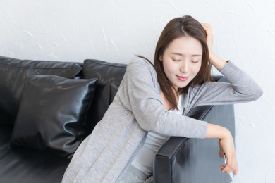 一名年轻女性趴在沙发边上闭眼休息