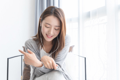 一名年轻女性坐在窗边跟别人打电话沟通