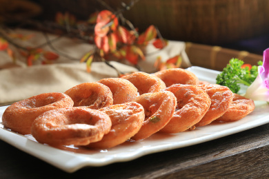 木板上白色长瓷盘里的整齐放着的面窝