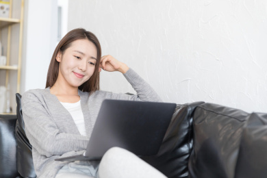 一名年轻女性躺在沙发上看电脑追剧