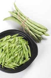 保健蔬菜一盘四季豆丝与一捆四季豆摆放在桌面上