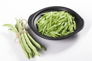保健蔬菜一盘四季豆丝与一捆四季豆摆放在桌面上
