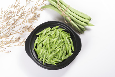 保健蔬菜一盘四季豆丝与一捆四季豆摆放在桌面上