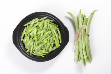 保健蔬菜一盘四季豆丝与一捆四季豆摆放在桌面上