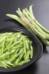保健蔬菜一盘四季豆丝与一捆四季豆摆放在桌面上