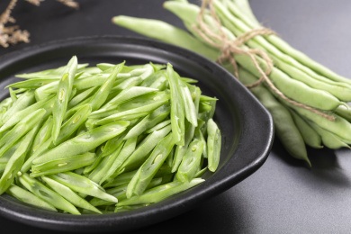 保健蔬菜一盘四季豆丝与一捆四季豆摆放在桌面上