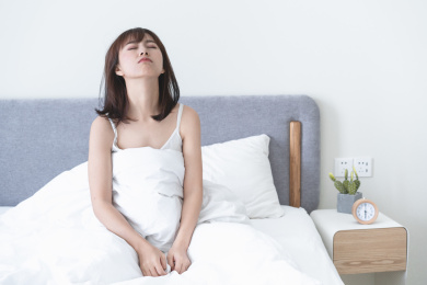 睡眼朦胧的年轻女性在床上半坐起身