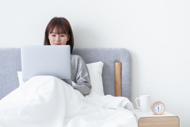 年轻女性坐在床上认真用电脑办公