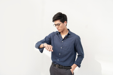 一名年轻的商务男士在室外等待时看手表