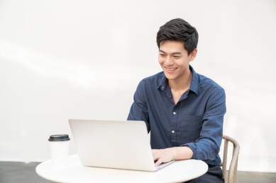 一名年轻的商务男士在户外坐在椅子上使用电脑