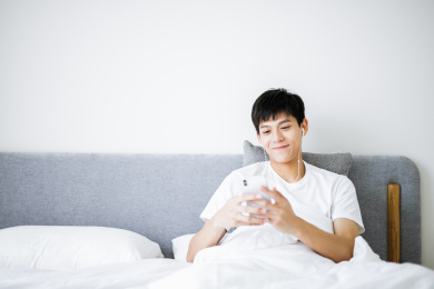 卧室里的男孩在床上使用手机听音乐