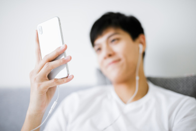 卧室里的男孩在床上使用手机听音乐