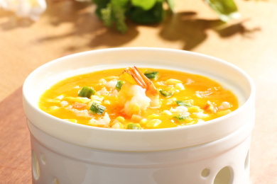 木板上带加热底座的白色瓷盅里的金汤鲜虾养生羹